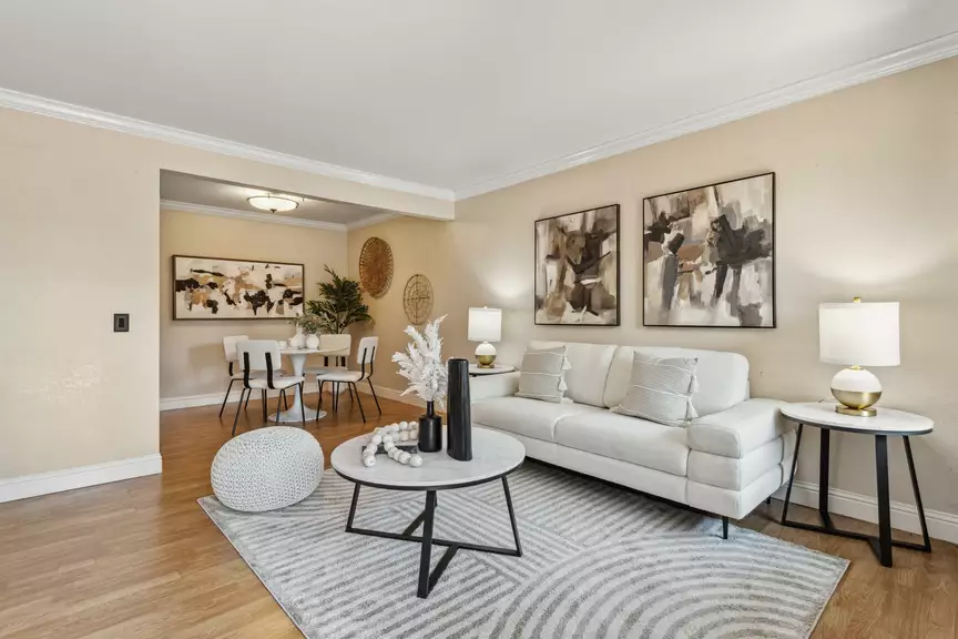 Bright modern living room with white sofa, round coffee table and adjacent dining nook