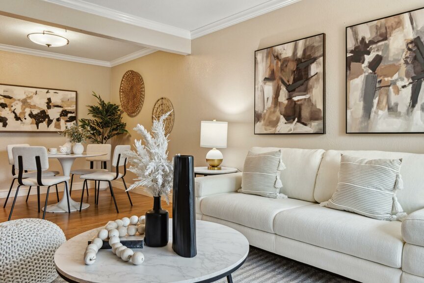 Bright living room with white sofa, marble coffee table and adjacent dining area