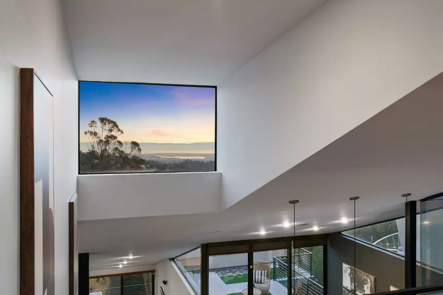 Modern double-height living area with large windows and sunset view