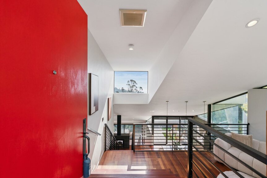 Modern entry foyer with red front door, hardwood floors and open railing