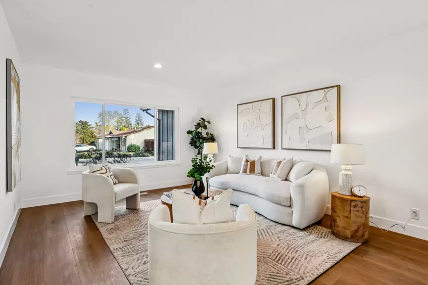 Bright modern living room with curved sofa, armchairs and large window