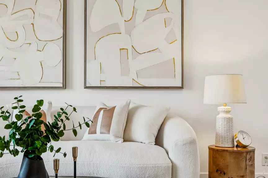 Bright modern living room with white sofa, abstract art, plant and side table lamp