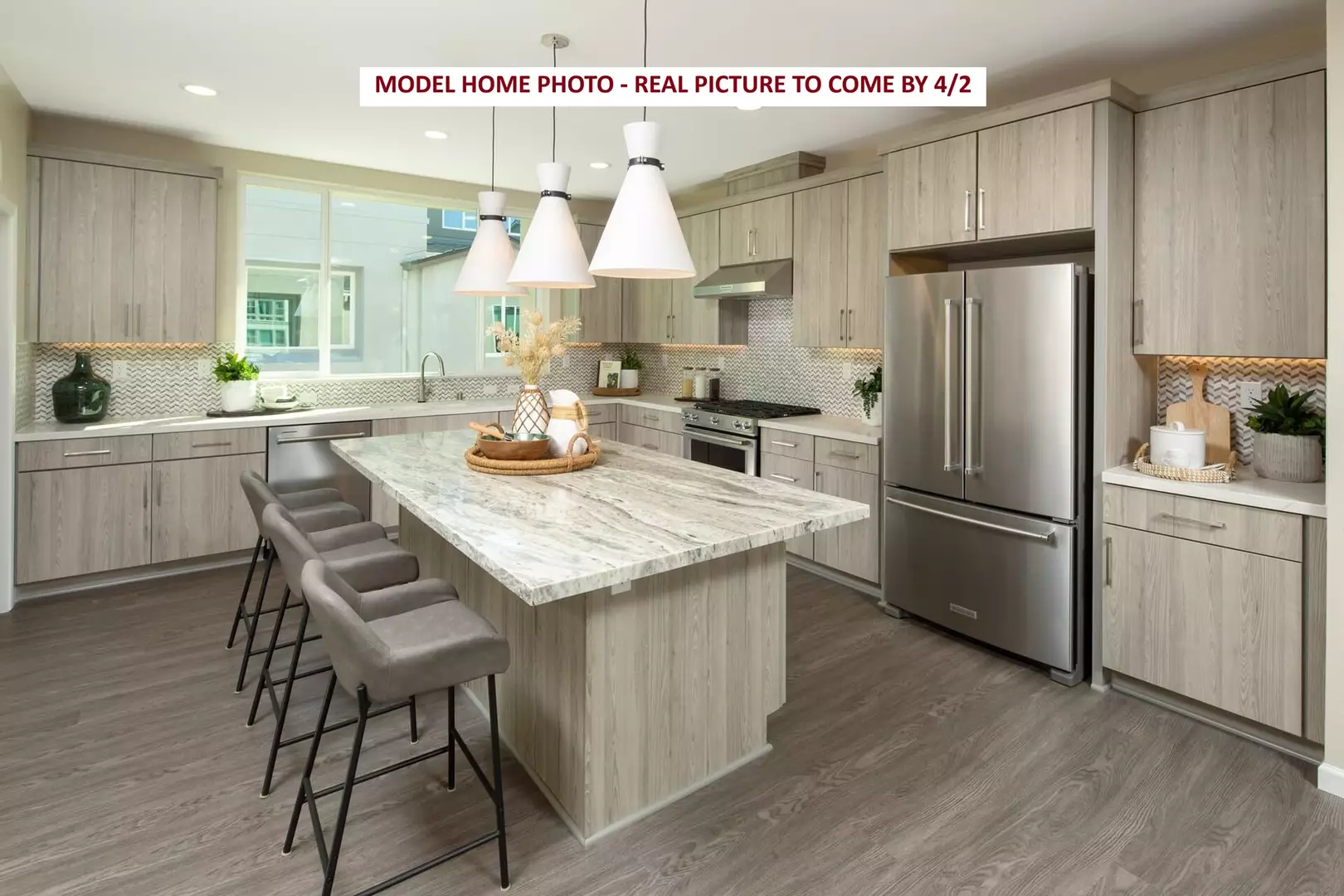 Modern kitchen with large island, pendant lights, and stainless steel appliances