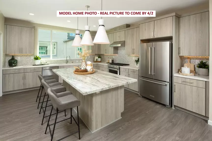 Modern kitchen with large island, pendant lights, and stainless steel appliances